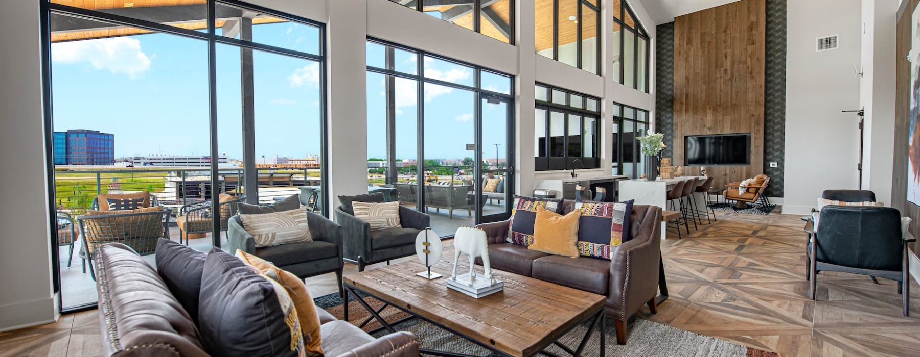 Resident lounge at Alta at the Farm Apartments in Allen, TX, featuring couches and floor to ceiling windows.