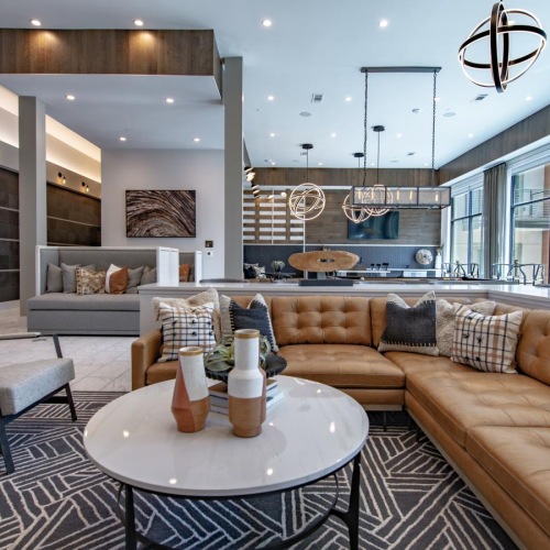 Quick access to state-of-the-art amenities a clubhouse room with a large couch, chairs, a table and large windows